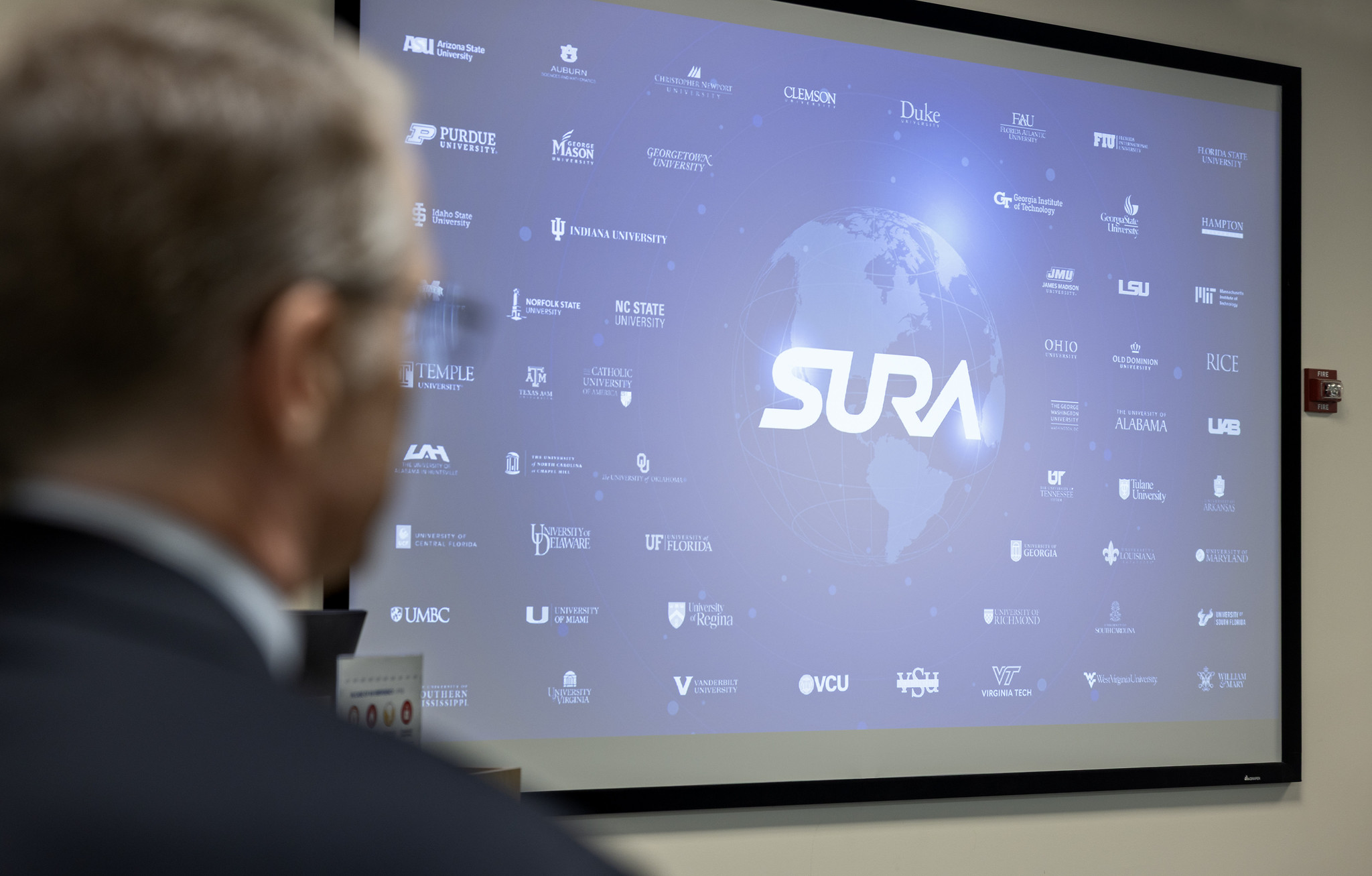 SURA Globe | Photo Credit: Aileen Devlin | Jefferson Lab SURA logo over globe surrounded by member university logos on a screen